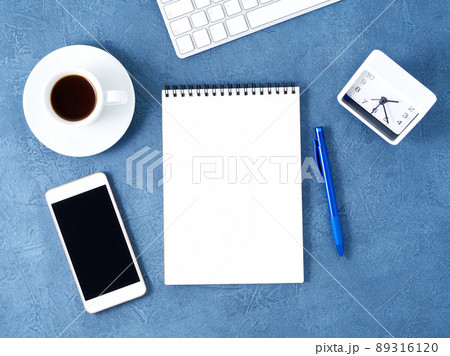 The open notepad with clean white page, pen and coffee cup on aged dark blue stone table, top view 89316120