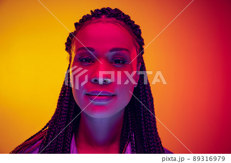 Closeup portrait of calm girl looking at camera isolated on yellow pink background in neon light. Concept of beauty, art, fashion, youth and emotions Closeup portrait of calm girl looking at camera isolated on yellow pink background in neon light. Concept of beauty, art, fashion, youth and emotions 89316979