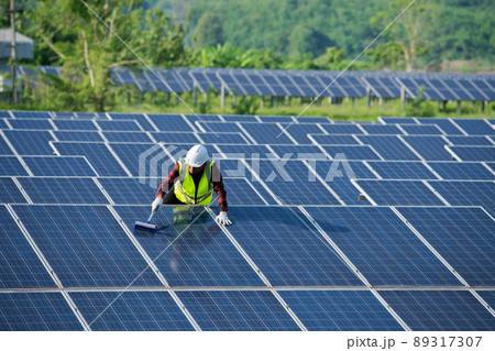 Cleaning solar panels by workers in uniform safety at solar farm 89317307