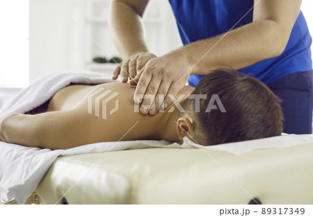 Masseur in modern health center performs therapeutic body massage for young man. Masseur in modern health center performs therapeutic body massage for young man. 89317349