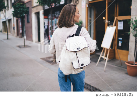 Unrecognizable trendy woman with backpack strolling on street Unrecognizable trendy woman with backpack strolling on street 89318505