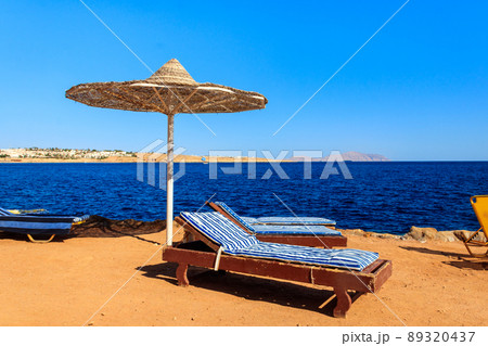 Sun umbrellas and chaise lounges on tropical beach. Concept of rest, relaxation, holidays, resort 89320437