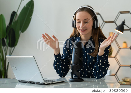 A young woman is recording an online podcast for her online show. An attractive woman using headphones in front of a microphone for a radio program. A young woman is recording an online podcast for her online show. An attractive woman using headphones in front of a microphone for a radio program. 89320569