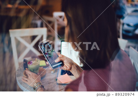 Woman holding mobile phone creating content for share in social networks on break in cafe Woman holding mobile phone creating content for share in social networks on break in cafe 89320974