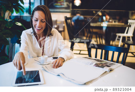 Cheerful female customer touching screen of gadget checking received email message and laughing, 89321004