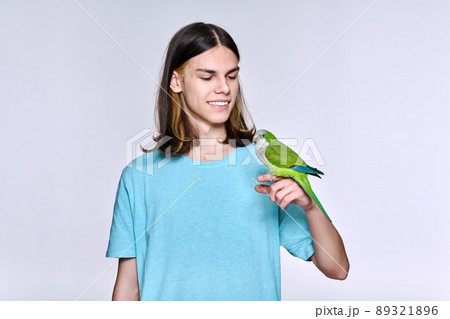 Young male with domestic green Quaker parrot on light studio background 89321896