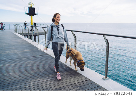 Active young woman with dog walking on promenade 89322043