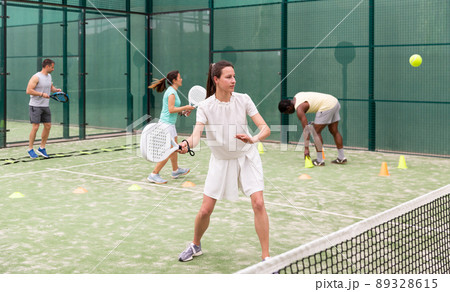 Woman playing padel. In the background, athletes are training 89328615