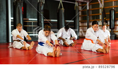 Group of people in kimono stretching before karate training 89328796