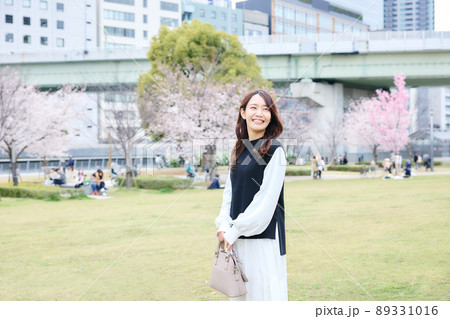 公園の芝生を歩く女性 89331016