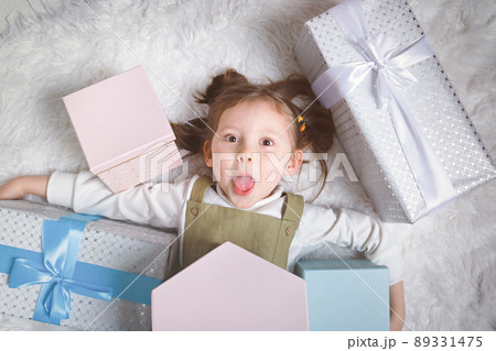 Happy girl sticks out her tongue because she received a lot of New Year's gifts Happy girl sticks out her tongue because she received a lot of New Year's gifts 89331475