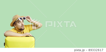 Surprised traveler with his holiday suitcase looking at something on copy space background Surprised traveler with his holiday suitcase looking at something on copy space background 89332617