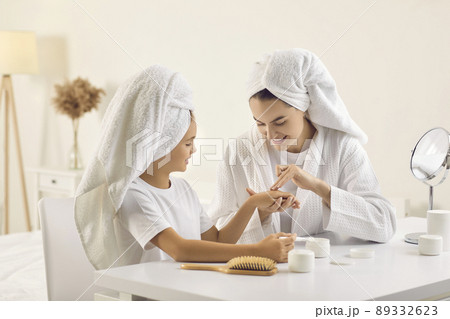 Happy beautiful mom and her child in white towels doing skin care routine together Happy beautiful mom and her child in white towels doing skin care routine together 89332623