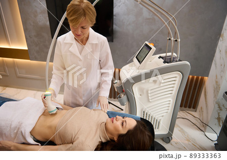 Attractive brunette with beautiful aesthetic body receiving non-surgical body shaping and anti-cellulite therapy in wellness clinic 89333363