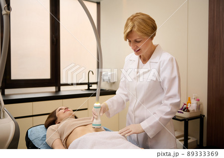 Experienced dermatologist cosmetologist gives body care procedures, anti-cellulite massage, ultrasound cavitation therapy for weight loss and body contouring in spa clinic 89333369
