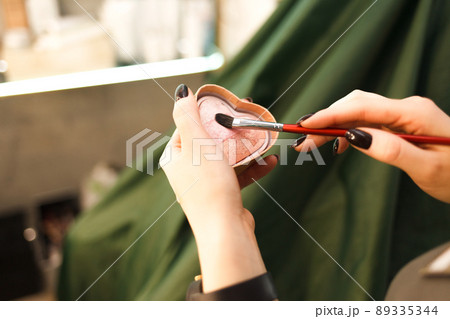 Makeup artist takes a blush with a brush straight from the palette. Makeup artist takes a blush with a brush straight from the palette. 89335344