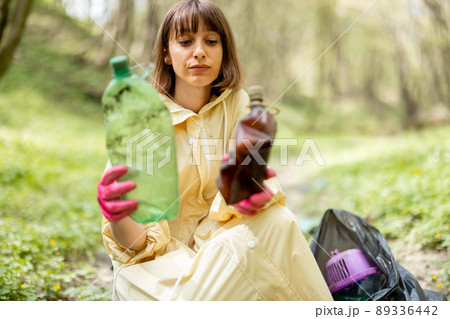 Woman collecting scattered plastic garbage in the woods Woman collecting scattered plastic garbage in the woods 89336442
