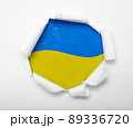 Ukrainian blue and yellow flag in the round hole in paper 89336720