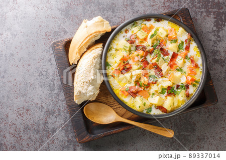 Homemade vegetable potatoes soup with smoked bacon closeup on the wooden tray. Horizontal top view 89337014