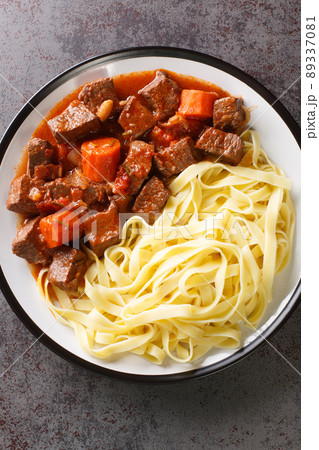 Daube Provencal French braised beef red wine, and vegetable stew served with egg noodles closeup in the plate. Vertical top view 89337081