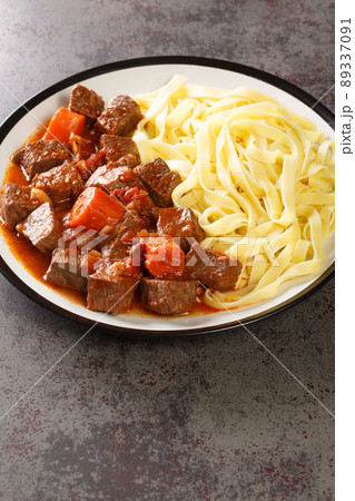 Daube Provencal French braised beef red wine, and vegetable stew served with egg noodles closeup in the plate. Vertical 89337091