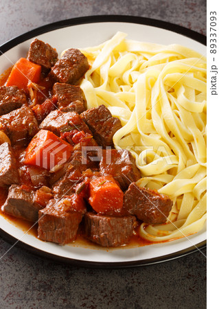 Daube Provencal classic French stew beef is slow simmered to tenderness served with noodles closeup in the plate. Vertical 89337093