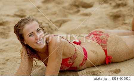 Sexy woman in a bikini relaxes on a sandy beach at the ocean Sexy woman in a bikini relaxes on a sandy beach at the ocean 89340606