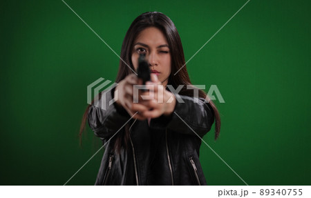 Young female agent with a gun in her hand shoots at the camera 89340755
