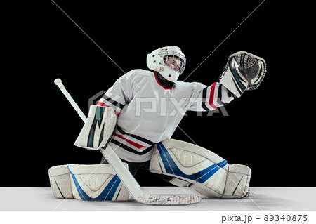 Dynamic portrait of teen boy, hockey player, goalkeeper catching puck with special glove isolated over black studio background Dynamic portrait of teen boy, hockey player, goalkeeper catching puck with special glove isolated over black studio background 89340875