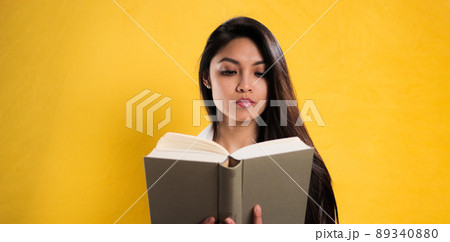 Young woman reads a book against a neutral background 89340880