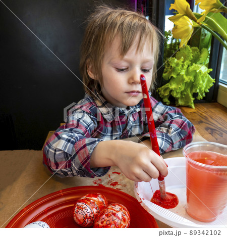 The child preparing for Easter. Paint eggs. Red paint egg. The child preparing for Easter. Paint eggs. Red paint egg. 89342102