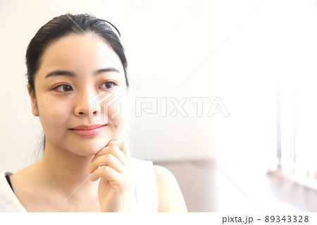 頬に手を触れる女性の顔横目線 頬に手を触れる女性の顔横目線 89343328