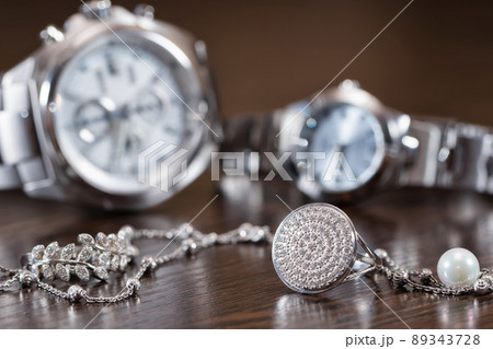 Silver rings and chain lying on background chrome watches 89343728