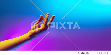 Studio shot of aethentic human hand isolated on gradient purple-blue background in neon light. Concept of human relation, community, togetherness Studio shot of aethentic human hand isolated on gradient purple-blue background in neon light. Concept of human relation, community, togetherness 89344064