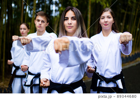 people high kicks during training of taekwondo outdoors bamboo background 89344680