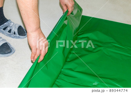 Laying green foil on the concrete floor under the sleepers before laying the floor panels. Laying green foil on the concrete floor under the sleepers before laying the floor panels. 89344774