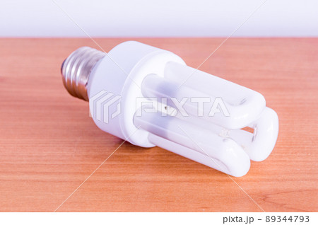 Compact fluorescent lamp on wooden table. Compact fluorescent lamp on wooden table. 89344793
