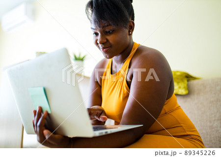 mixed race woman working by laptop in living room 89345226