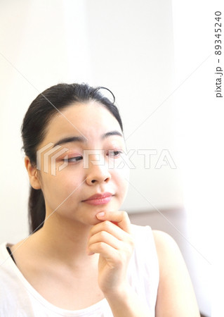 顎に手を触れる怪訝な表情の女性の顔 89345240