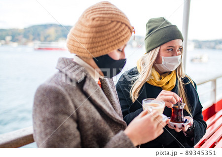 two women drinking turkish tea and salep while wearing medical mask coronavirus time two women drinking turkish tea and salep while wearing medical mask coronavirus time 89345351