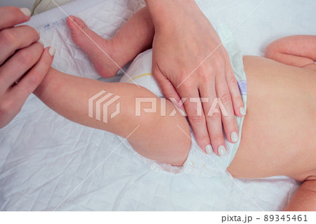 caucasian mother using wet wipes,applying baby powder before putting diapers on her four month old baby in bed at home 89345461