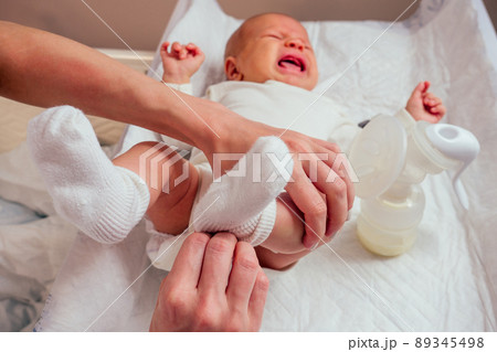 woman puts on socks and romper for baby making foot massage to her little child close up 89345498