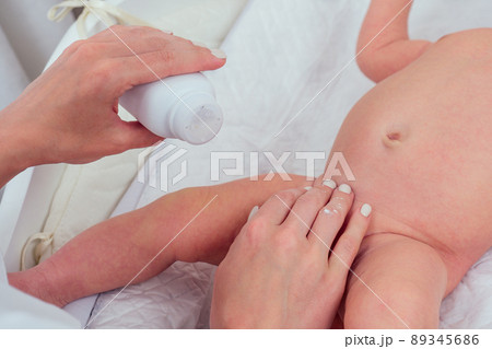 caucasian mother using wet wipes,applying baby powder before putting diapers on her four month old baby in bed at home caucasian mother using wet wipes,applying baby powder before putting diapers on her four month old baby in bed at home 89345686