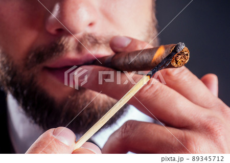 Portrait of an attractive business man with a cigar in black background studio Portrait of an attractive business man with a cigar in black background studio 89345712