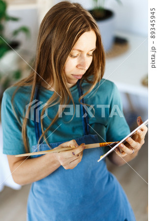 Woman artist holding paintbrush.Creative woman enjoying painting.Young beautiful woman in art studio, taking colorful paints from palette,creating masterpiece on easel, work, imagination Woman artist holding paintbrush.Creative woman enjoying painting.Young beautiful woman in art studio, taking colorful paints from palette,creating masterpiece on easel, work, imagination 89345945