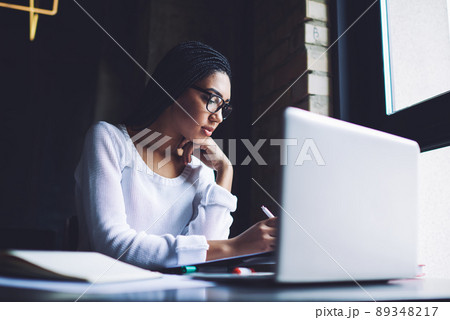 Serious woman working with documents and laptop Serious woman working with documents and laptop 89348217