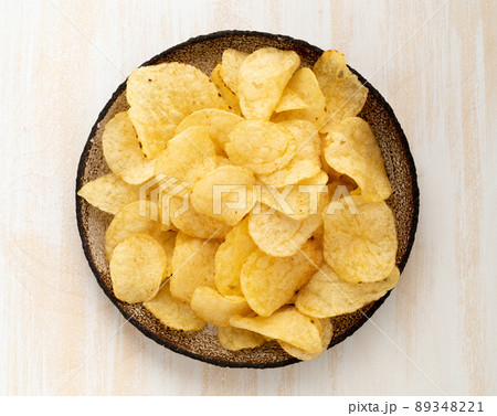 brown yellow chips from natural potato in brown ceramic plate on white wooden background 89348221