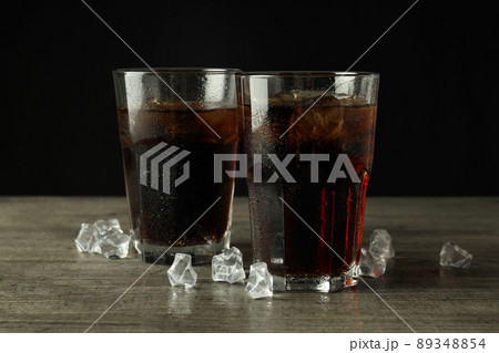 Glass of cola and ice on gray textured table Glass of cola and ice on gray textured table 89348854