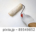 Male hand painting wall with roller. Renovating with white color paint 89349852