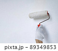 Male hand painting wall with roller. Renovating with white color paint 89349853